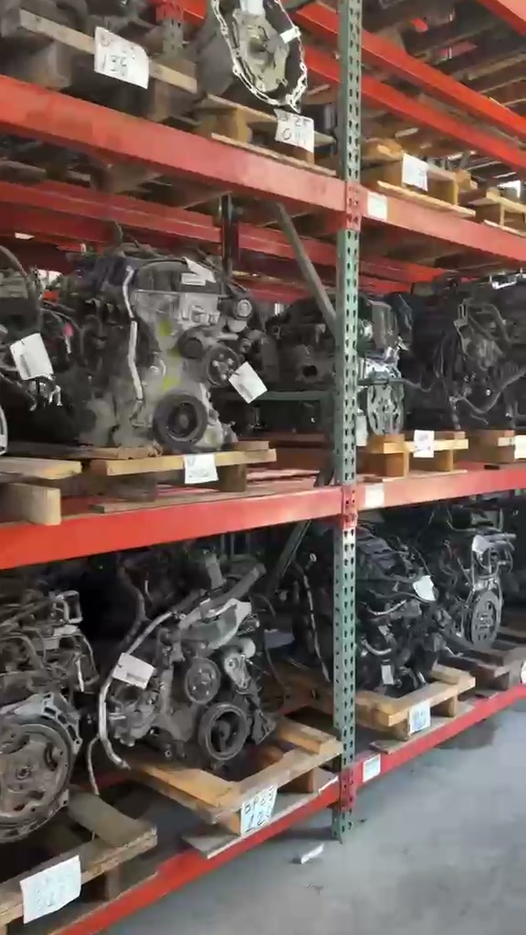 Used engines on pallets in red warehouse racking, each with a white stock tag